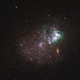 UGCA 281, a blue compact dwarf galaxy. Within it, two giant star clusters appear brilliant white and are swaddled by greenish hydrogen gas clouds.